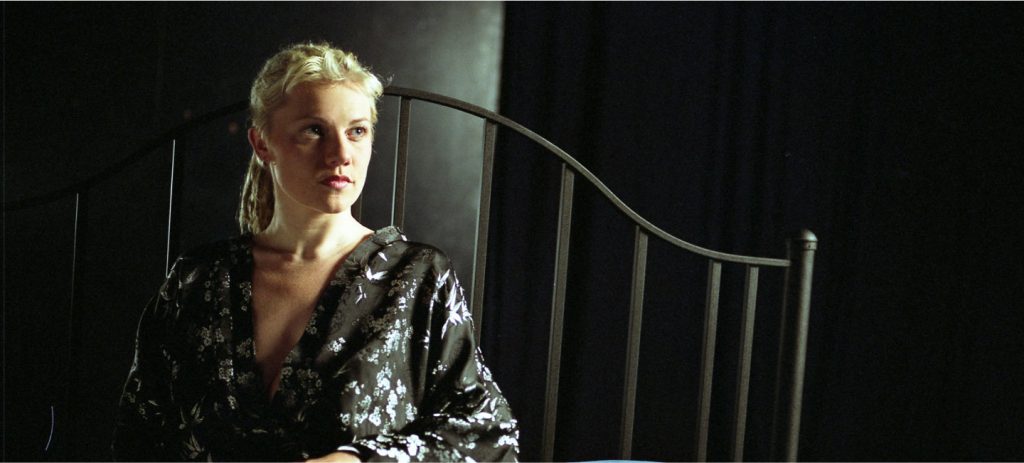 Alicia Whitsover waits onstage on the bed  in her bathrobe in Matinee, an erotic film directed by Jennifer Lyon Bell for Blue Artichoke Films